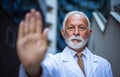 Mature serious doctor. Gesturing with hand. Royalty Free Stock Photo