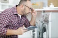 mature serviceman putting on eyeglasses to examine washing machine Royalty Free Stock Photo