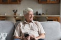 Mature single man sits on sofa with modern smartphone