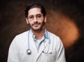 Mature and skilled doctor in labcoat poses in dark background