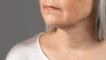 Mature skin care. Cropped view of senior woman& x27;s face with wrinkles around lips and on neck, grey studio background Royalty Free Stock Photo