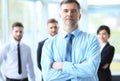Mature smiling business manager crossing his arms in front of his business team. Royalty Free Stock Photo