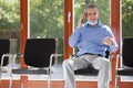 Mature smiling businessman talking on smart phone in an empty waiting room of an office
