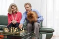 Mature smiling couple playing chess in a bright living room Royalty Free Stock Photo