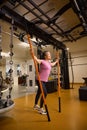 Mature smiling european woman doing sport exercise with sports sticks in gym
