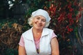 A mature smiling female gardener or woman sitting in the garden with scarf on her head Royalty Free Stock Photo