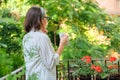 Mature smiling happy woman with cup of coffee relaxing at home on open terrace Royalty Free Stock Photo