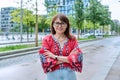 Mature smiling woman in embroidered shirt looking at camera, on street of modern city Royalty Free Stock Photo