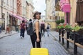 Mature smiling woman traveling in tourist city with suitcase