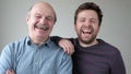 Mature son and father together chortling . Two men having fun.
