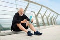 Mature sportsman having break, drinking water, using smartphone Royalty Free Stock Photo