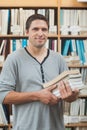 Mature student posing in library holding a pile of books Royalty Free Stock Photo