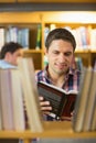 Mature student reading book by shelf in the library Royalty Free Stock Photo