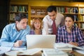 Mature students with teacher and laptop in library Royalty Free Stock Photo
