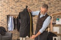 Mature tailor taking measurements of jacket on mannequin in atelier Royalty Free Stock Photo