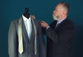 Mature tailor taking measurements of jacket on mannequin in atelier Royalty Free Stock Photo