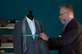 Mature tailor taking measurements of jacket on mannequin in atelier Royalty Free Stock Photo