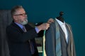 Mature tailor taking measurements of jacket on mannequin in atelier Royalty Free Stock Photo