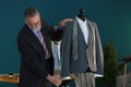 Mature tailor taking measurements of jacket on mannequin in atelier Royalty Free Stock Photo