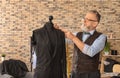 Mature tailor taking measurements of jacket on mannequin in atelier Royalty Free Stock Photo