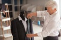 Mature tailor taking measurements of male jacket on mannequin in atelier Royalty Free Stock Photo