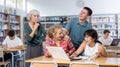 Mature teacher urges noisy teenagers to be quiet in school library Royalty Free Stock Photo