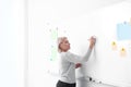 Mature teacher writing on whiteboard in classroom Royalty Free Stock Photo