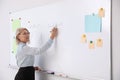 Mature teacher writing on whiteboard in classroom Royalty Free Stock Photo