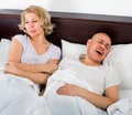 Mature tired evil girl looking at snoring boyfriend Royalty Free Stock Photo