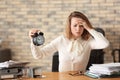 Mature tired woman with alarm clock at table in office. Time management concept Royalty Free Stock Photo