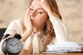 Mature tired woman with alarm clock at table in office. Time management concept Royalty Free Stock Photo