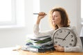 Mature tired woman with clock at table in office. Time management concept Royalty Free Stock Photo