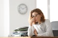 Mature tired woman with documents at table in office. Time management concept Royalty Free Stock Photo