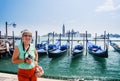 Mature tourist woman stays against row of gondolas
