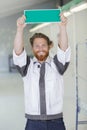 mature tradesman holding blank sign with green background