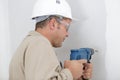 Mature tradesman using drill on interior wall