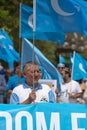 A mature Uyghur men in the pro-Uyghur demonstration holding the banner and flag