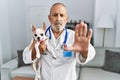 Mature veterinarian man checking dog health with open hand doing stop sign with serious and confident expression, defense gesture Royalty Free Stock Photo