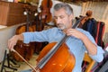 Mature violin maker while testing violins in laboratory Royalty Free Stock Photo