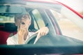 Mature woman adjusting make-up, putting on lipstick while driving a car Royalty Free Stock Photo