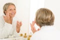 Mature woman apply cream looking bathroom mirror Royalty Free Stock Photo