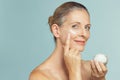 Mature woman applying skin cream on face Royalty Free Stock Photo