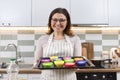 Mature woman in apron with baking tray with cupcakes being prepared Royalty Free Stock Photo