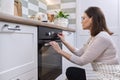 Mature woman in apron near the oven in the kitchen