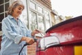 Mature Woman Attaching Charging Cable To Environmentally Friendly Zero Emission Electric Car At Home Royalty Free Stock Photo