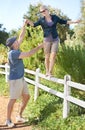 Ive got you.... A mature woman balancing on a fence while being helped by her husband.