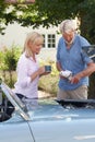 Mature Woman Bringing Hot Drink To Man Restoring Classic Sports Car Working On Engine Under Hood Royalty Free Stock Photo