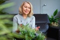 Mature woman caring home flowers.Flower plants at house