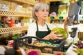 Lady cahsier weighting melon at counter in greengrocer Royalty Free Stock Photo