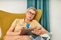 Mature woman in casuals paying by credit card while online shopping from home Royalty Free Stock Photo